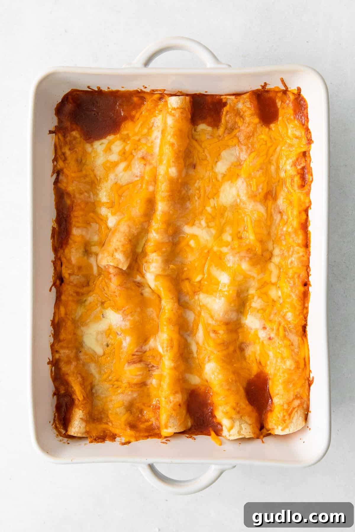 Garnished Cheese Enchiladas Ready to Serve A casserole dish showcasing beautifully baked cheese enchiladas, garnished with an array of fresh toppings like cilantro and sour cream.