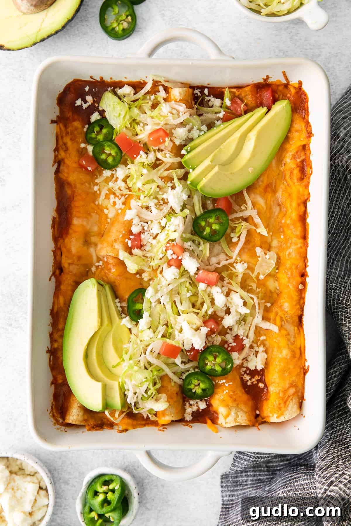 Perfectly Baked and Garnished Cheese Enchiladas A close-up shot of cheese enchiladas in a casserole dish, richly garnished with fresh toppings like cilantro and sour cream, ready to be served.