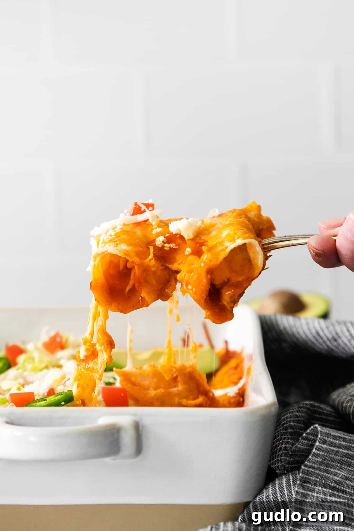 Serving Homemade Cheese Enchiladas A serving spoon lifting a cheesy enchilada from a casserole dish, showcasing the melted cheese and delicious filling.