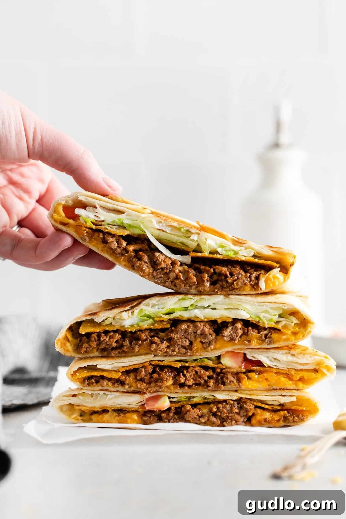 Homemade Cheesy Crunchwrap Supreme: Crispy, Cheesy, and Better Than Takeout! Four perfectly stacked homemade crunchwrap supremes on a plate, showcasing their golden-brown tortillas and delicious fillings.