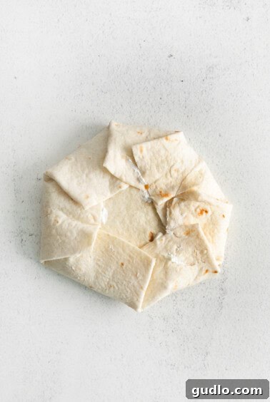 A partially folded crunchwrap supreme, showing the technique for sealing.