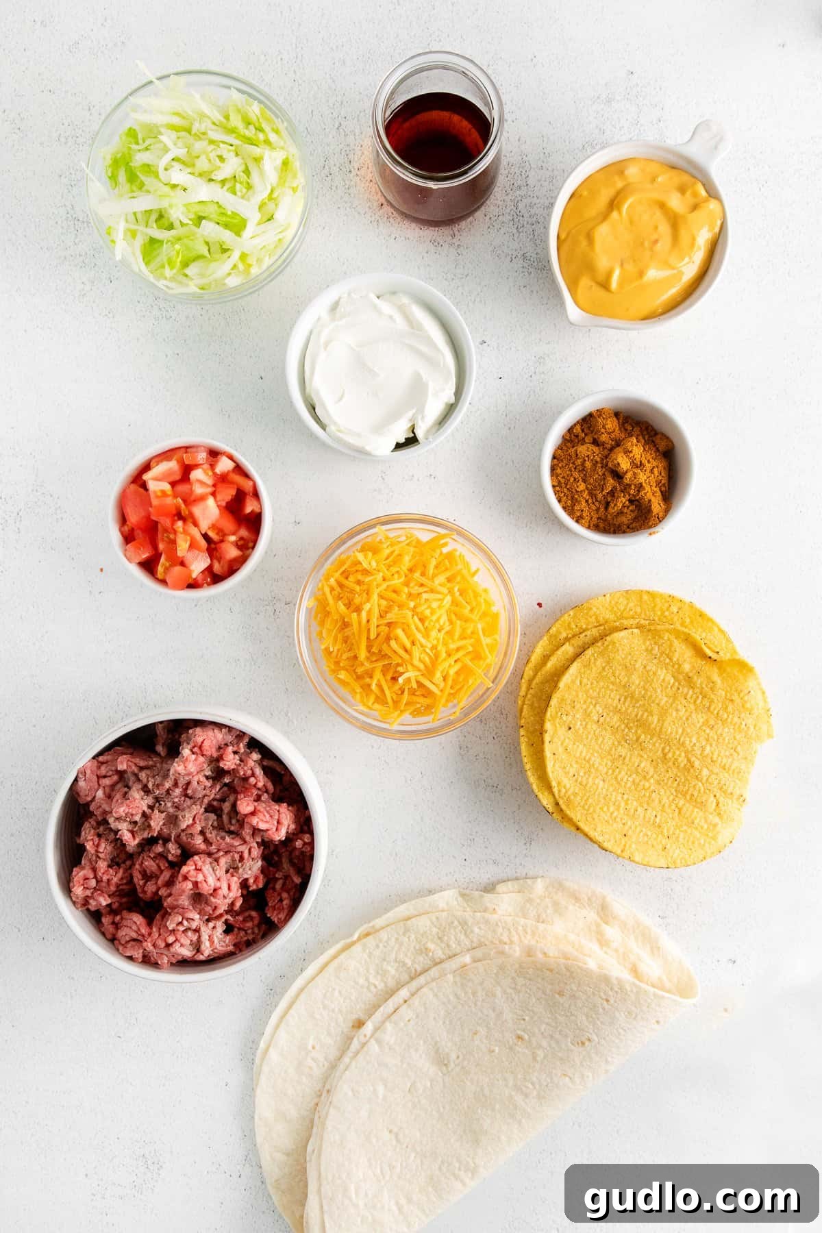 Fresh Ingredients for Your Perfect Homemade Crunchwrap Small bowls filled with fresh ingredients for crunchwrap supreme, including ground beef, shredded cheese, lettuce, tomatoes, and sauces.