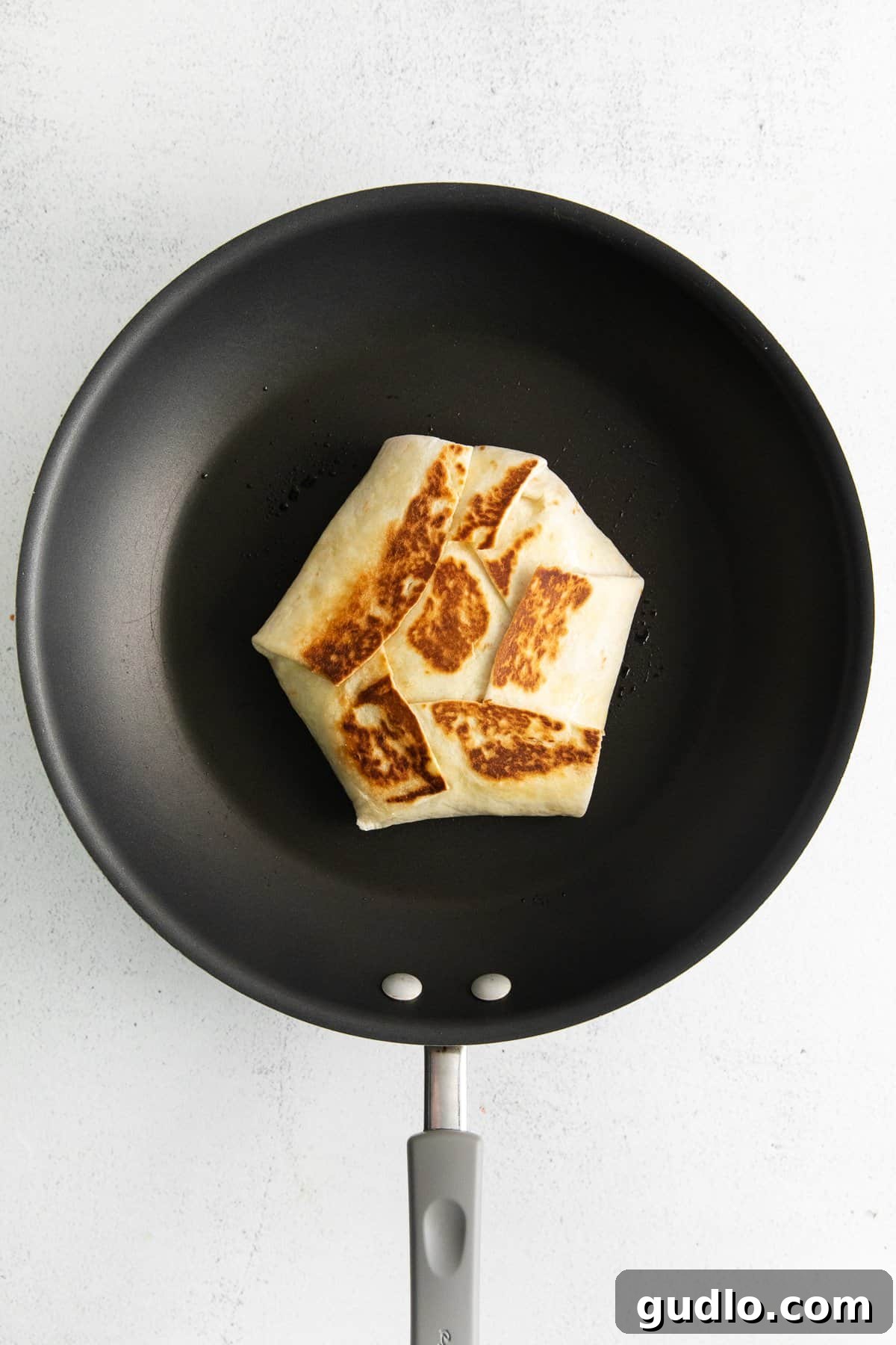 Sizzling Perfection: Cooking Your Crunchwrap A homemade crunchwrap supreme sizzling to a golden crisp in a hot skillet.