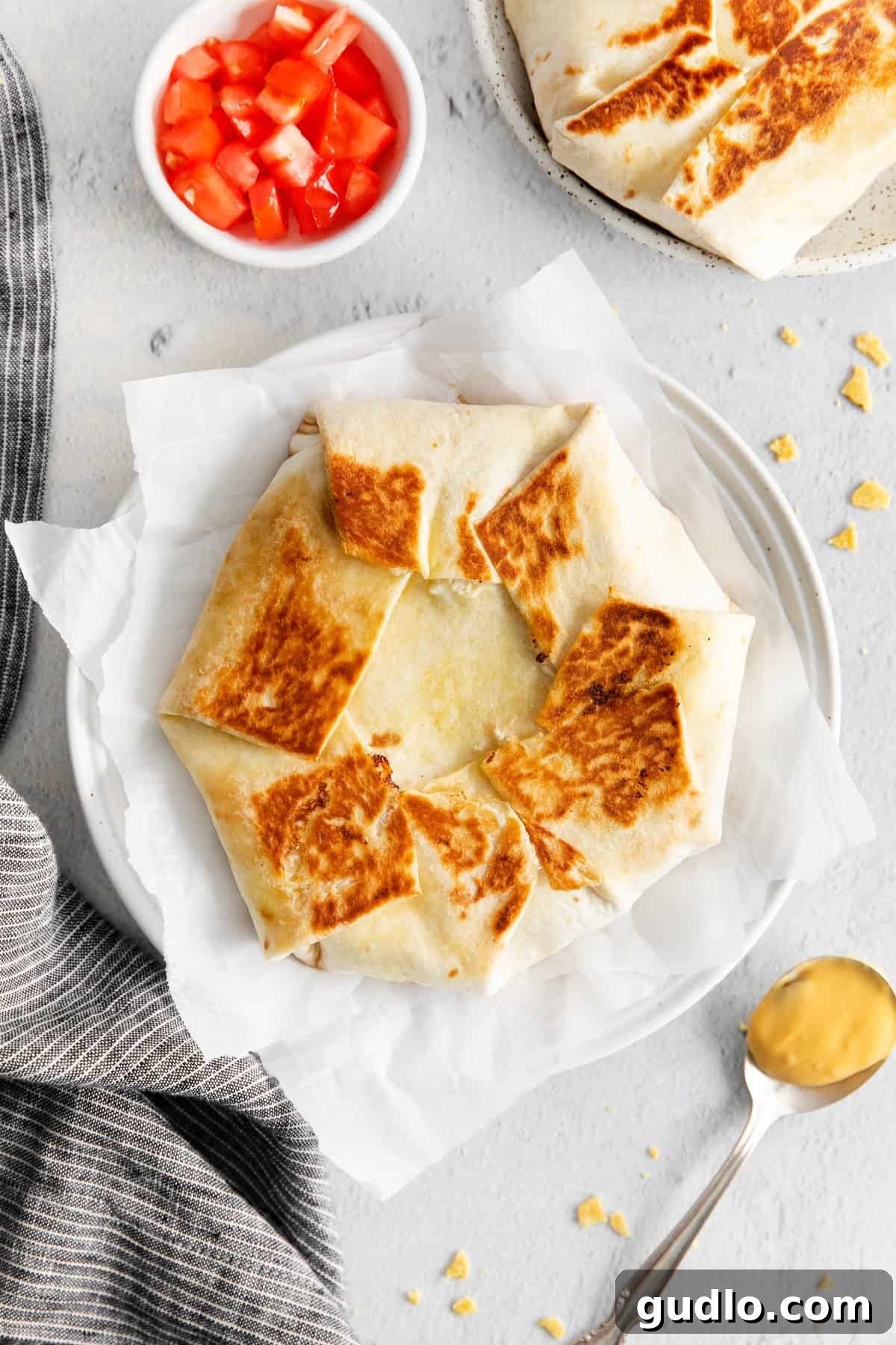 Ready to Enjoy: Your Perfect Homemade Crunchwrap A perfectly golden-brown crunchwrap supreme, sliced in half to reveal its mouth-watering layers, served on a white plate.