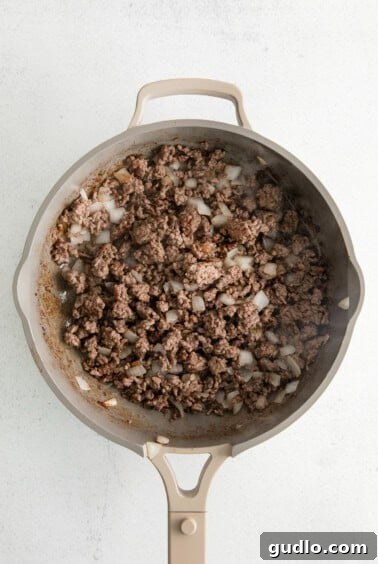 Cheesy Taco Bake 12 A skillet filled with cooked ground beef and sautéed onions.