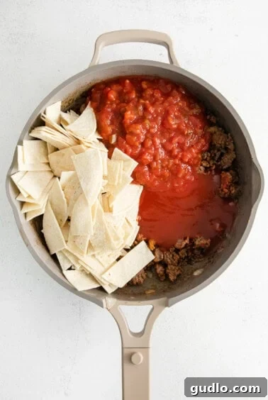 Cheesy Taco Bake 13 A frying pan with meat, salsa, and tortilla chips mixed together.