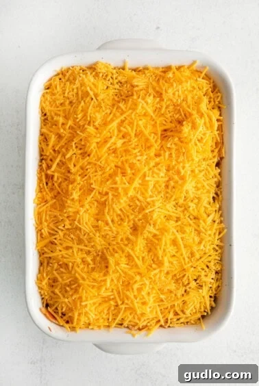 Cheesy Taco Bake 14 A casserole dish filled with the taco bake mixture and topped with shredded cheese, ready for the oven.