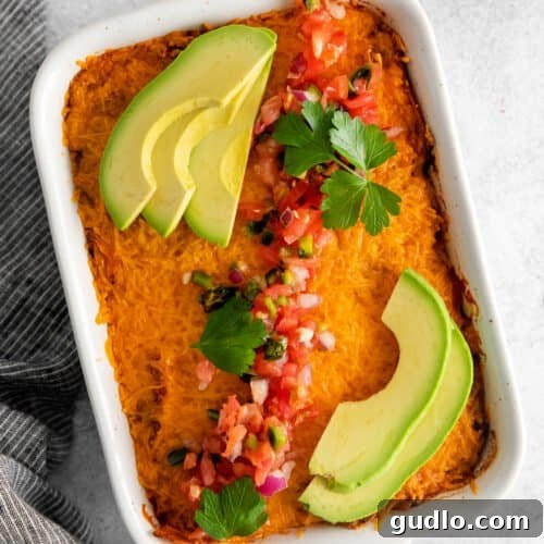 Cheesy Taco Bake 10 A white baking dish with a baked sweet potato casserole topped with avocado and cilantro.