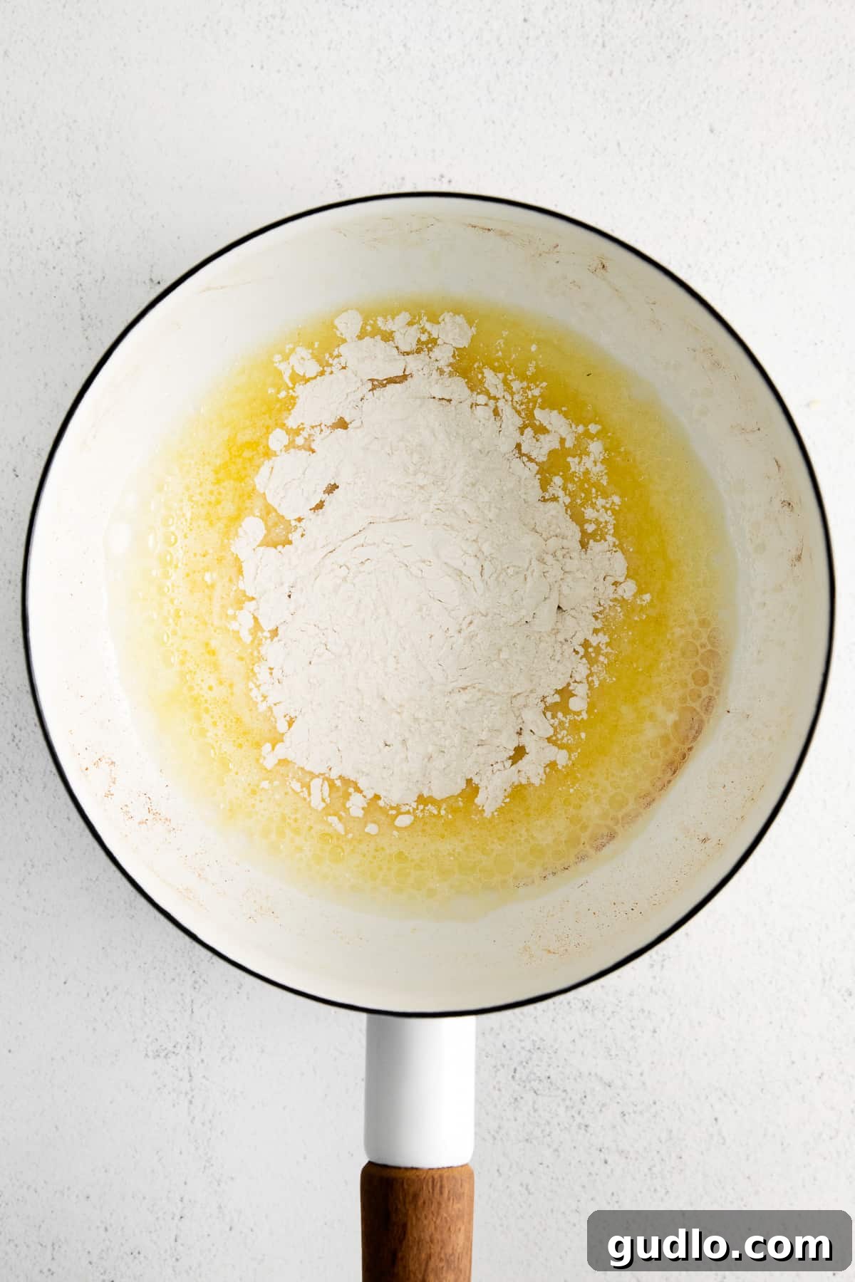 Melted butter and flour being whisked together in a saucepan over gentle heat, meticulously forming a perfect, pale blonde roux—the essential base for a velvety cheese sauce.