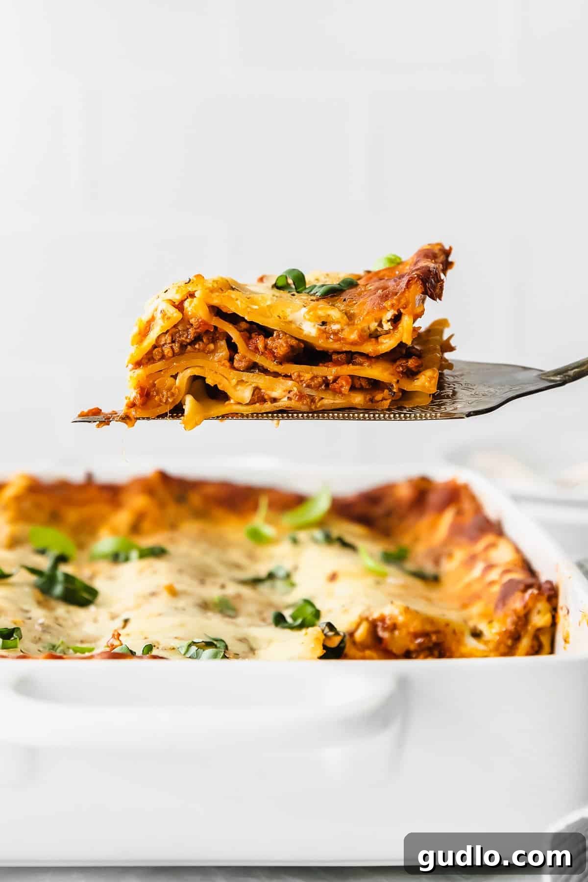 The Ultimate Bechamel Lasagna Recipe A perfectly sliced piece of bechamel lasagna being lifted from a baking dish with a spatula, revealing its beautiful layers.