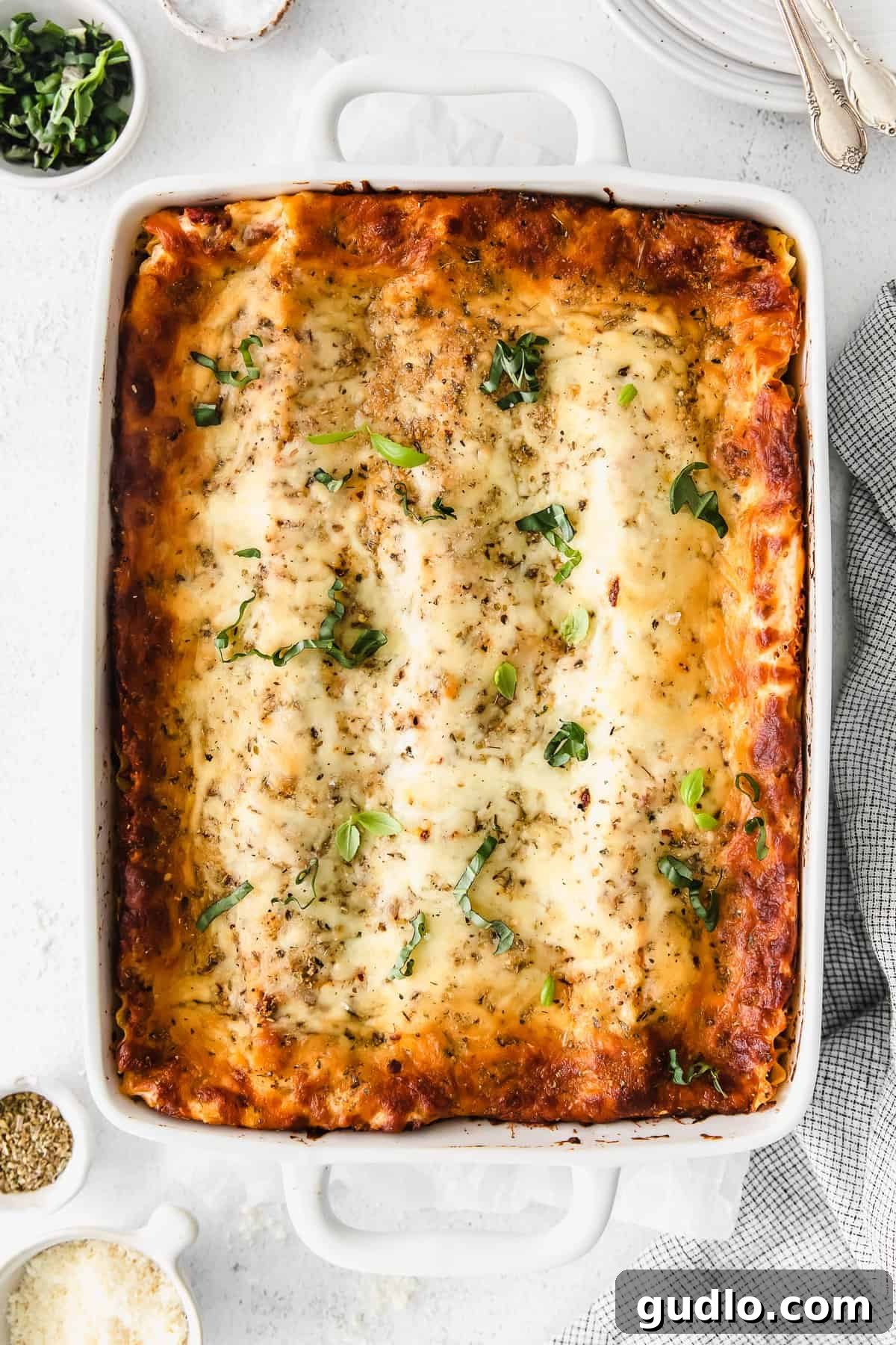 Baked Bechamel Lasagna The full bechamel lasagna baked to perfection in a white casserole dish, ready to be served.