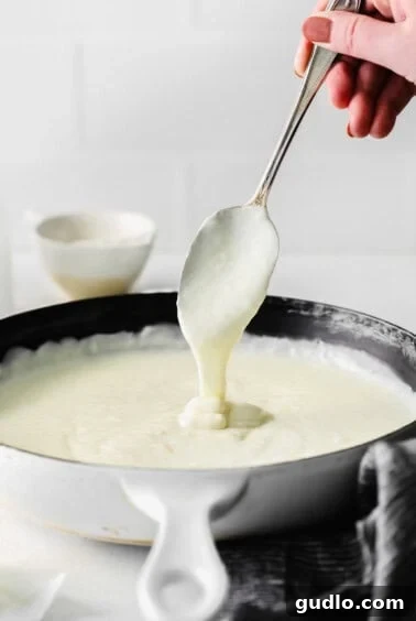 Creamy Bechamel Lasagna 9 A spoon coated in thick, creamy bechamel sauce, ready for the lasagna layers.