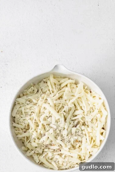 Creamy Bechamel Lasagna 10 A bowl of shredded mozzarella and parmesan cheese mixed with Italian seasoning, ready for the lasagna topping.