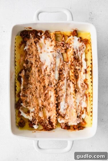 Creamy Bechamel Lasagna 11 Lasagna layers assembled in a white baking dish, showing noodles, meat sauce, and bechamel sauce.