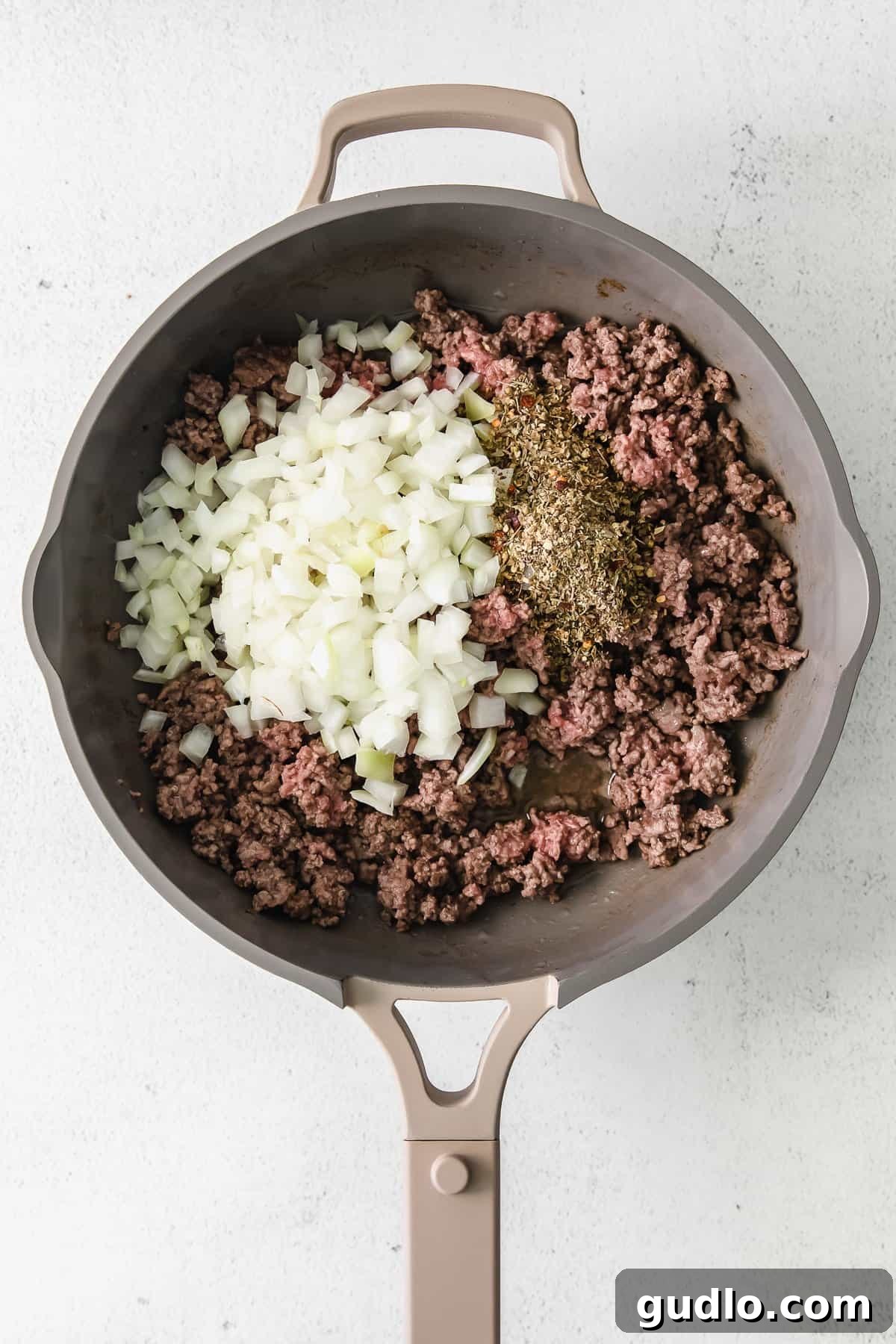 Ground Beef Browning in Skillet Sizzling ground beef browning in a large skillet, forming the base of the savory meat sauce.