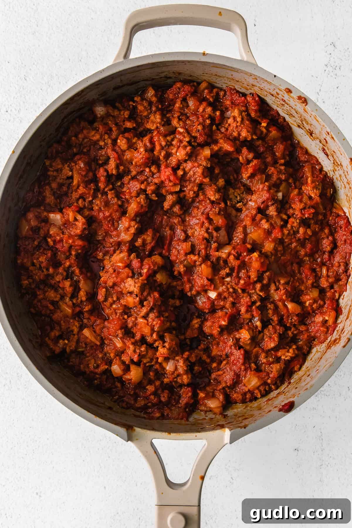 Simmering Meat Sauce The rich meat sauce simmering in a skillet, showcasing its vibrant red color and hearty texture.