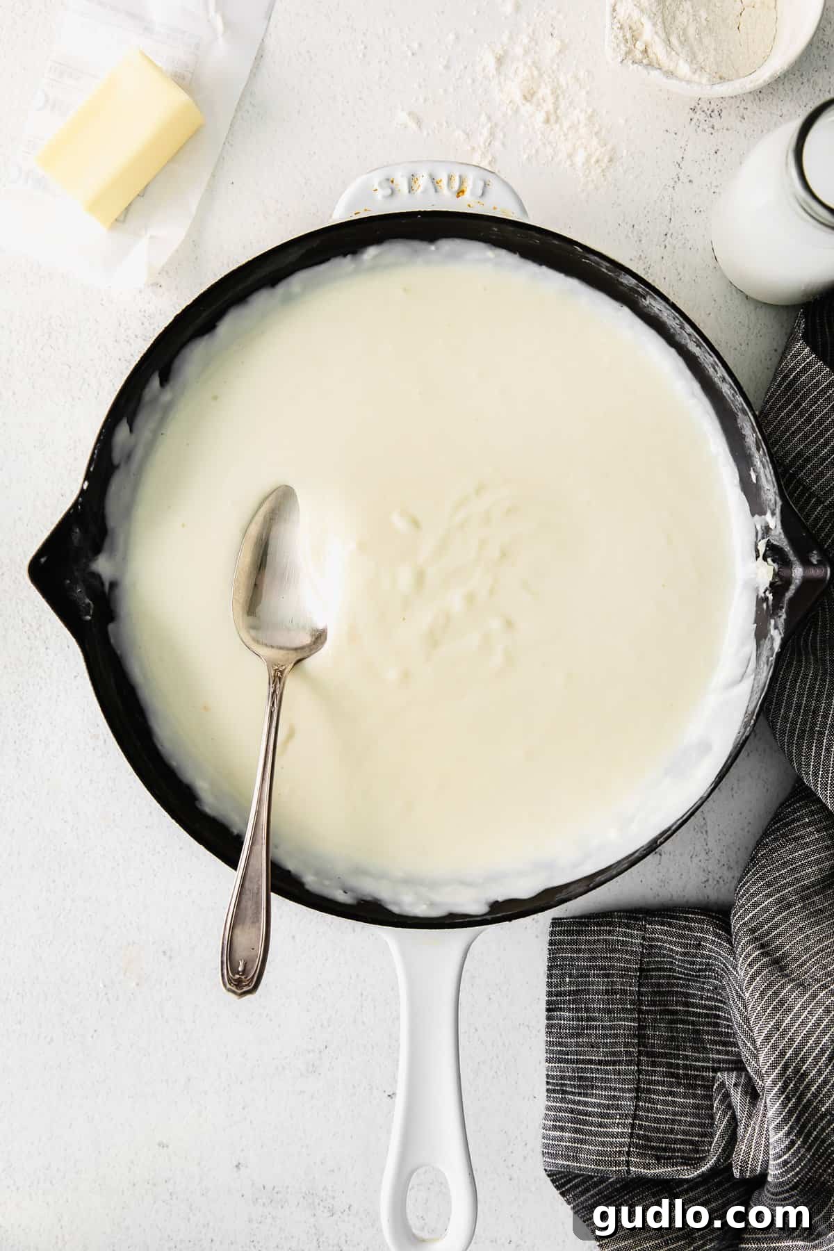 Learn how to make a creamy, white bechamel sauce recipe with just 3 basic ingredients - butter, flour, and milk. Creamy bechamel sauce in a cast iron pan, ready to be used.