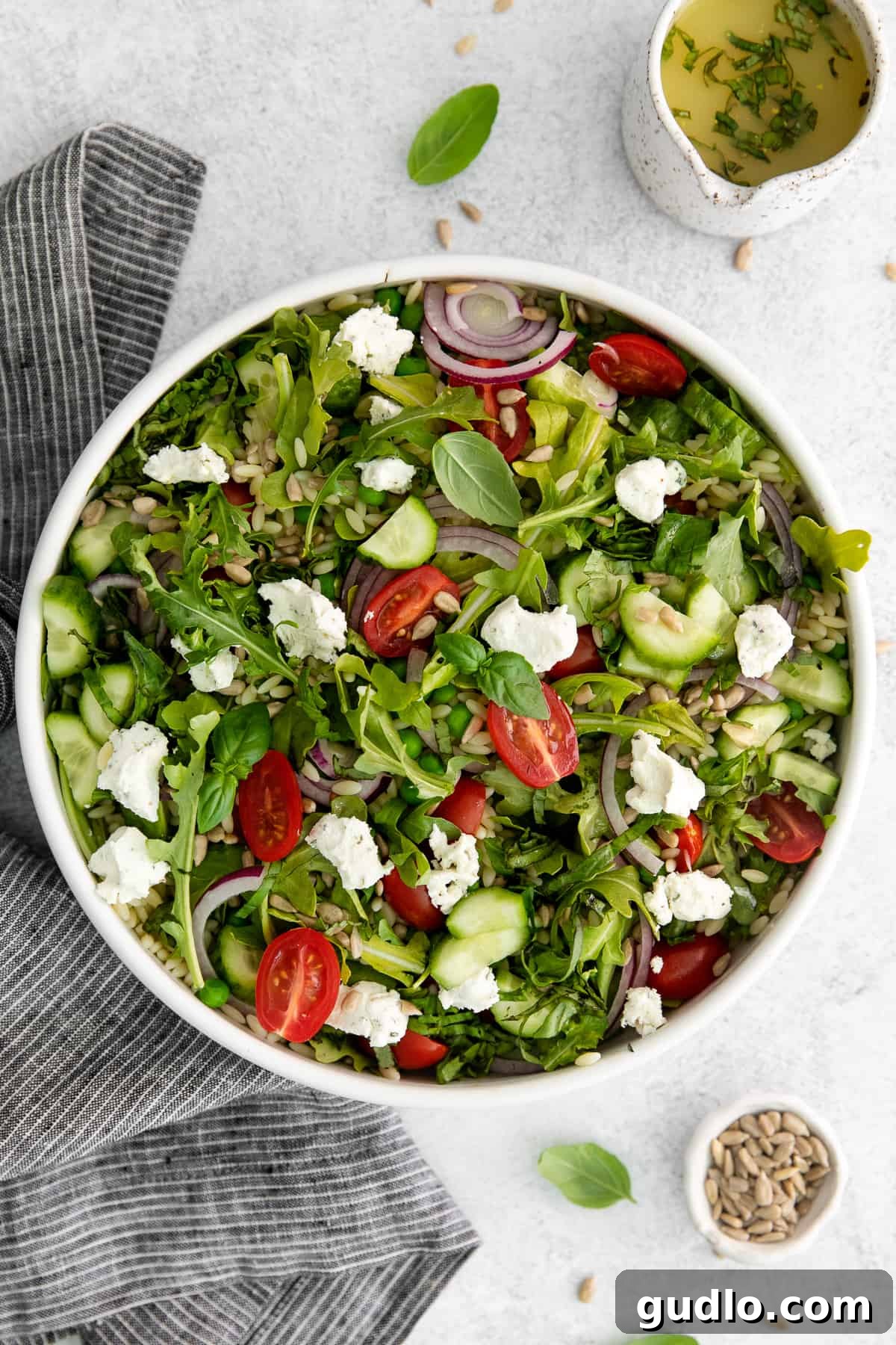 A vibrant lemon orzo salad with crumbled goat cheese in a white bowl, ready to be served.
