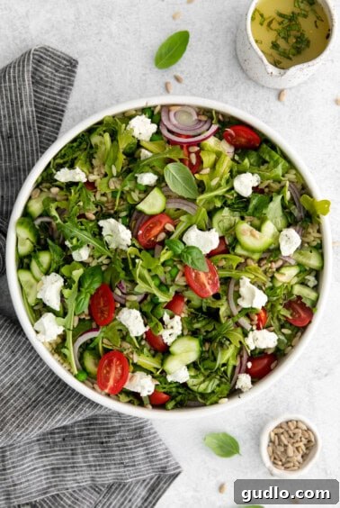 A close-up of the finished Lemon Orzo Salad with creamy goat cheese generously crumbled on top, ready to be served.