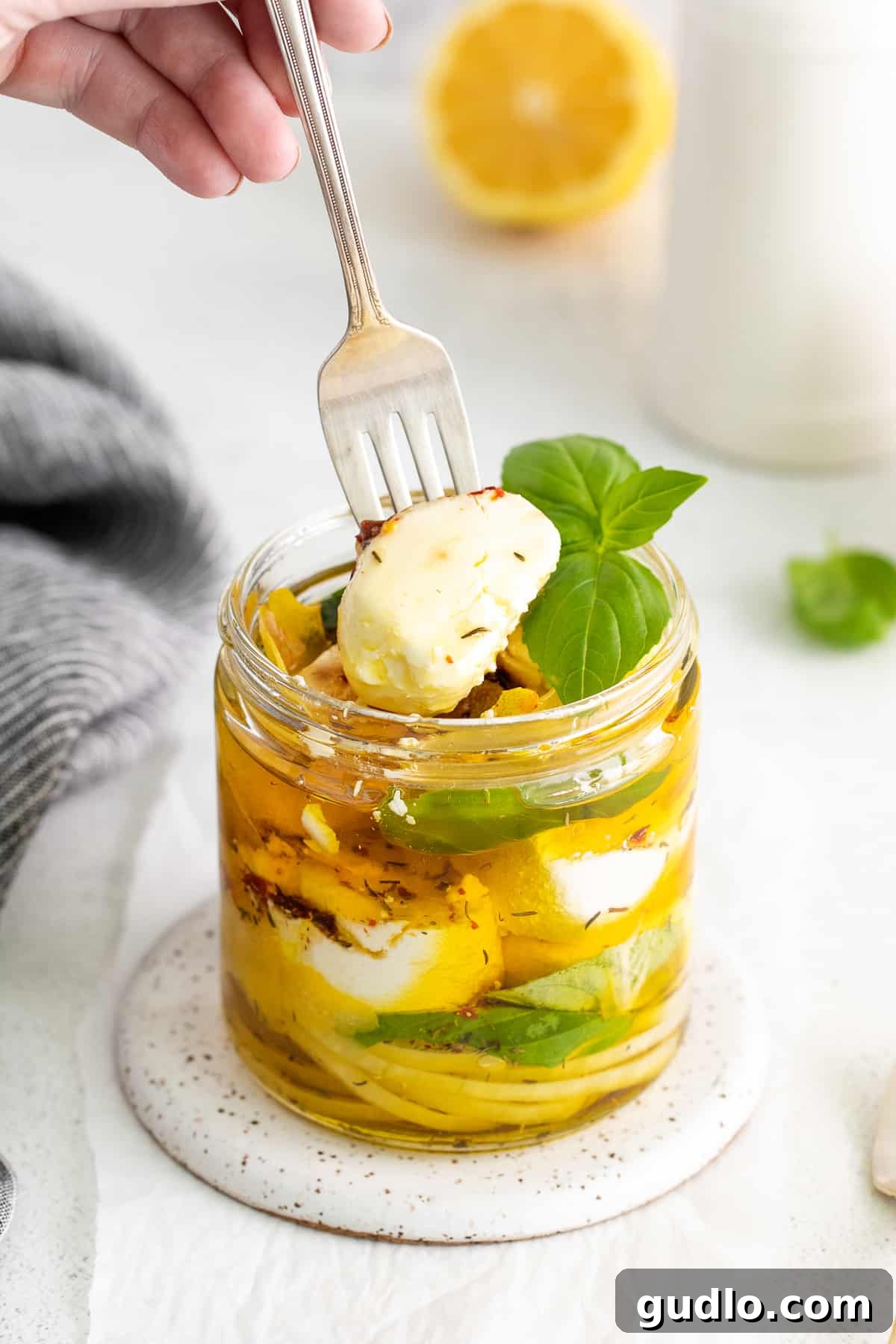 Herbed Olive Oil Marinated Goat Cheese 2 A fork spearing a chunk of marinated goat cheese, showcasing its creamy texture and herb infusion.