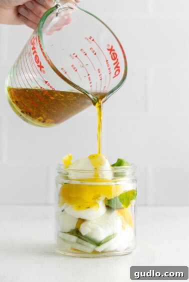 Pouring the marinade over goat cheese in a jar.