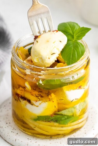 Taking a piece of marinated goat cheese out of the jar with a fork.