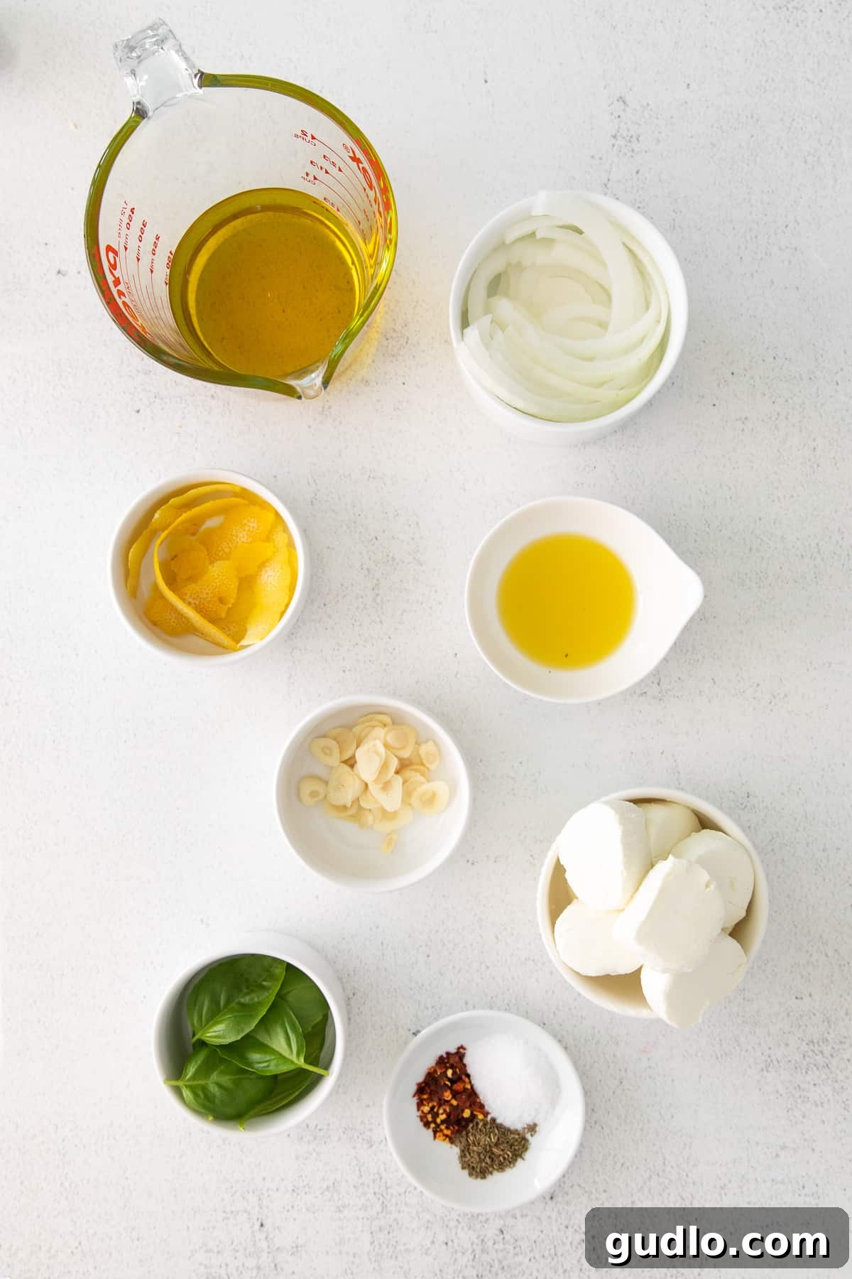 Herbed Olive Oil Marinated Goat Cheese 3 Small bowls filled with the fresh ingredients for marinated goat cheese, ready for preparation.