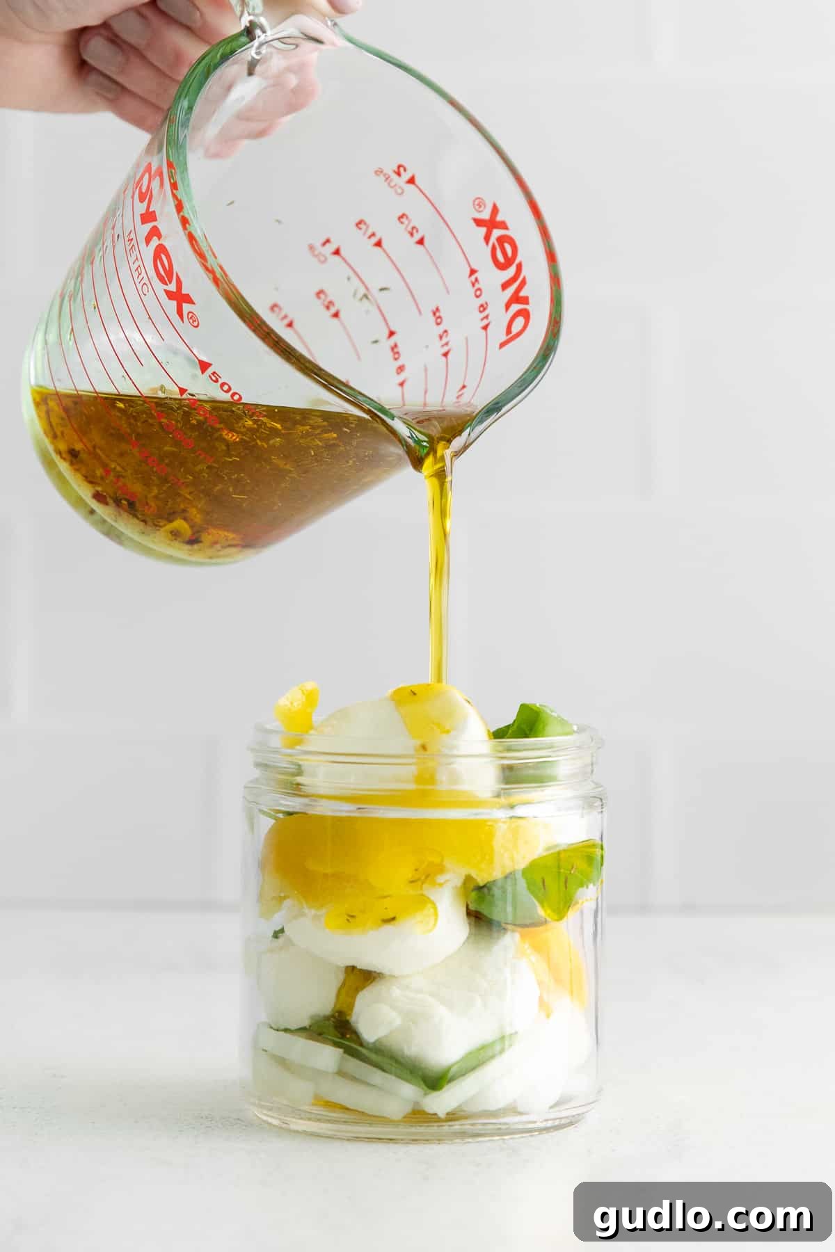 Herbed Olive Oil Marinated Goat Cheese 6 Carefully pouring the infused olive oil marinade over goat cheese, lemon, and basil in a jar.