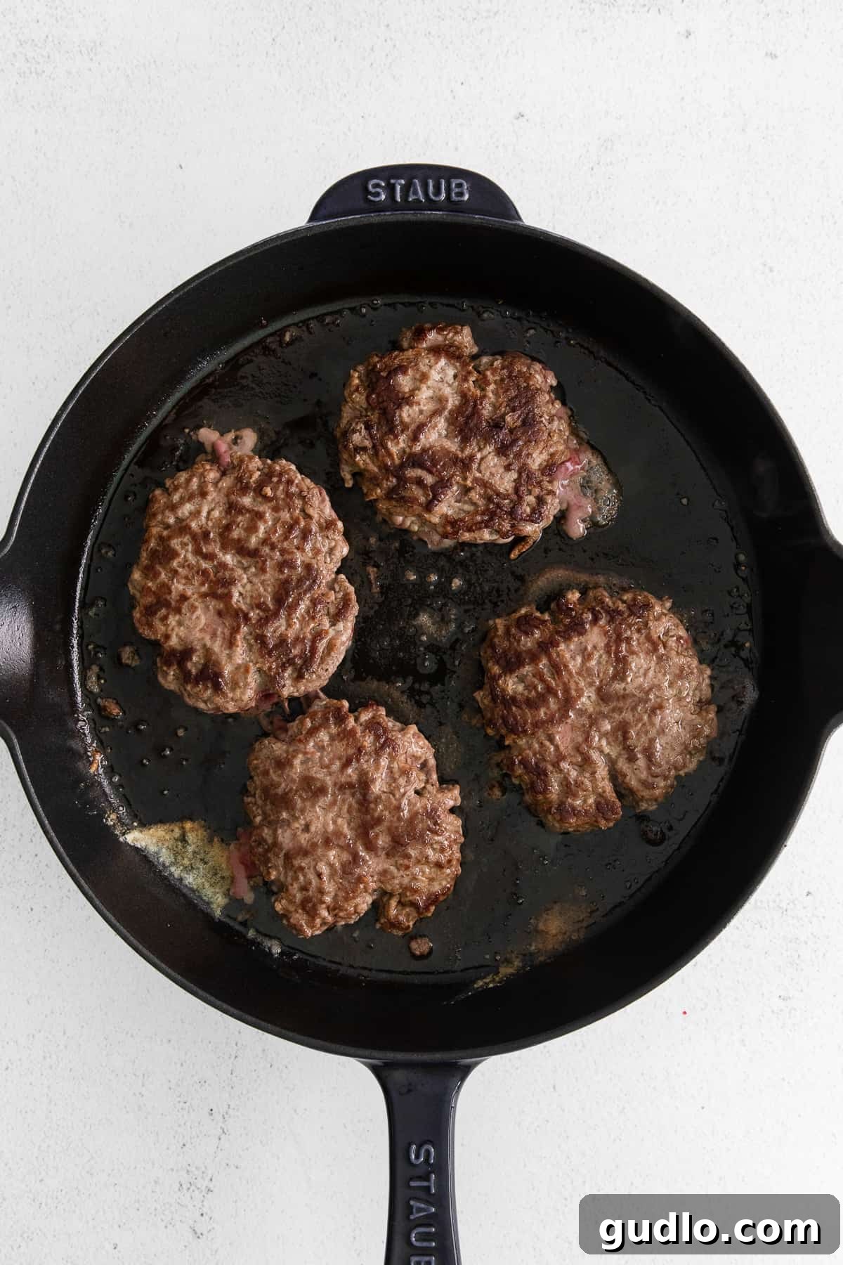 Searing Burger Patties Burger patties in a cast iron skillet, cooking to a perfect sear.
