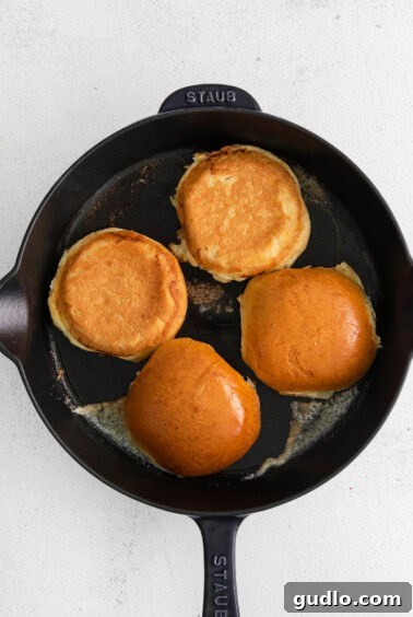 Easy Homemade Cheeseburgers 4 Hamburger buns being perfectly toasted in a skillet.