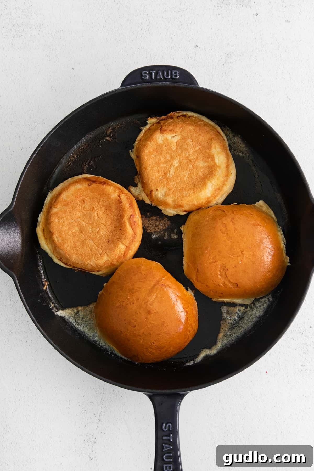 Toasting Buns for Your Cheeseburger Hamburger buns being toasted to a golden brown in a cast iron skillet.