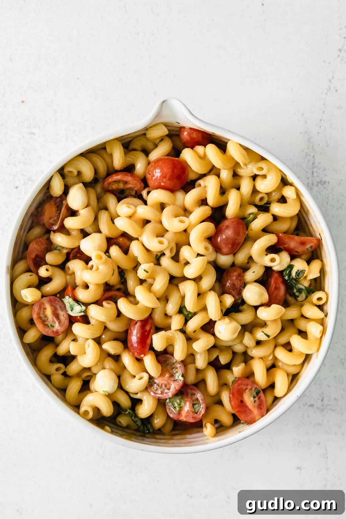 Vibrant Caprese Pasta Toss 5 A large bowl of vibrant Caprese Pasta Salad, generously tossed with dressing and ready to be served.