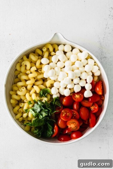 Caprese Pasta Salad ingredients in a bowl before dressing.