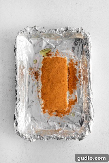 Seasoning being pressed into the cream cheese block.
