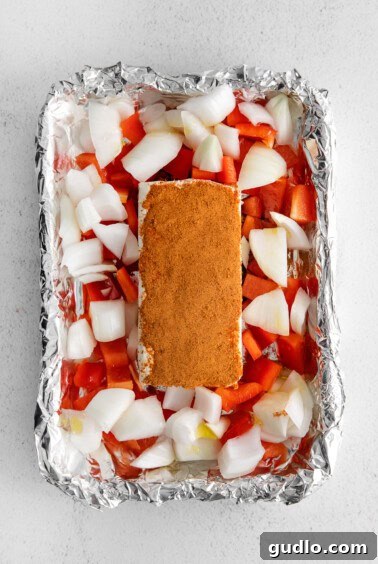 Cream cheese surrounded by vegetables in a foil boat.