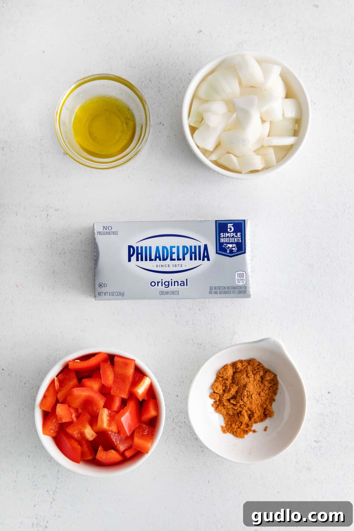 Gather your simple, high-quality ingredients to create a spectacular smoked cream cheese appetizer with ease. Fresh ingredients meticulously arranged for preparing smoked cream cheese, including a cold block of cream cheese, vibrant spice blends, and finely chopped vegetables like red bell pepper and white onion.