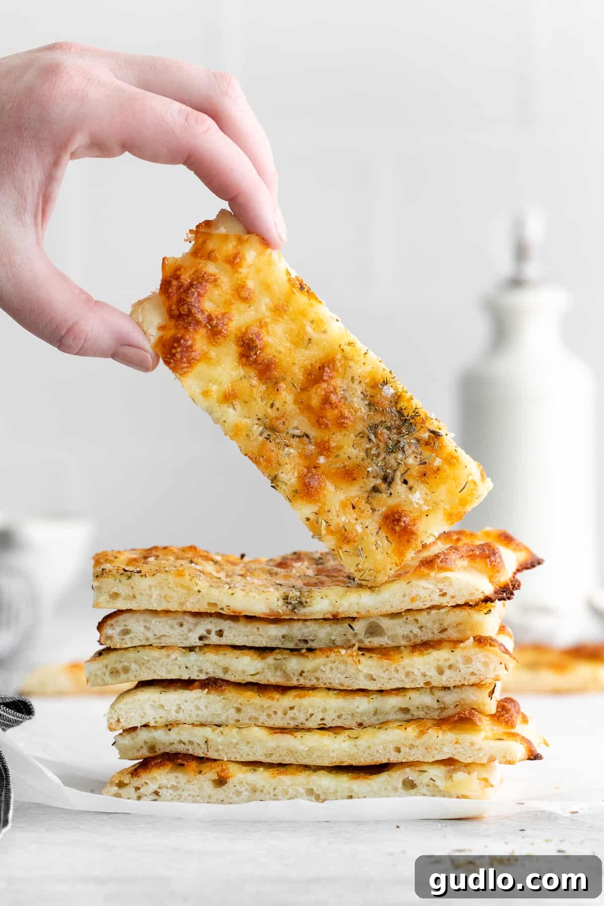 Irresistible Homemade Cheese Bread Slice A hand holding a slice of golden-brown homemade cheese bread, showcasing its cheesy topping.