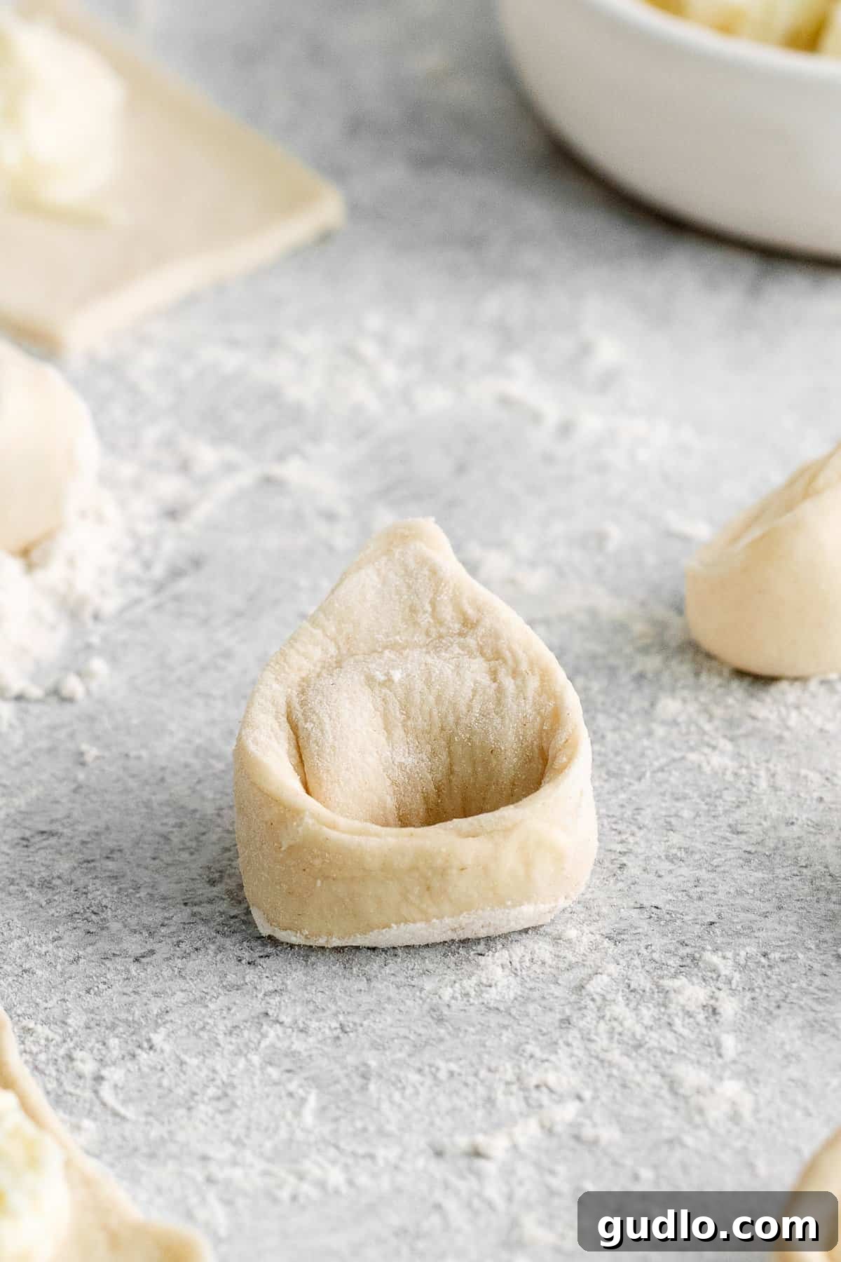 Freshly made cheese tortellini arranged on a cutting board, ready to be cooked or frozen.