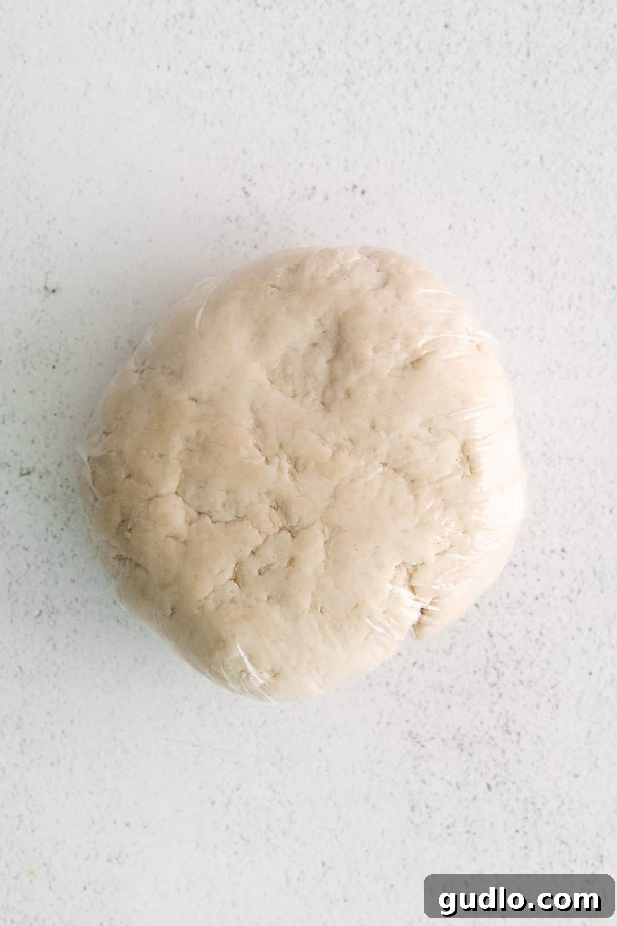 Smooth, perfectly kneaded pasta dough ball resting on a floured surface, ready for rolling.