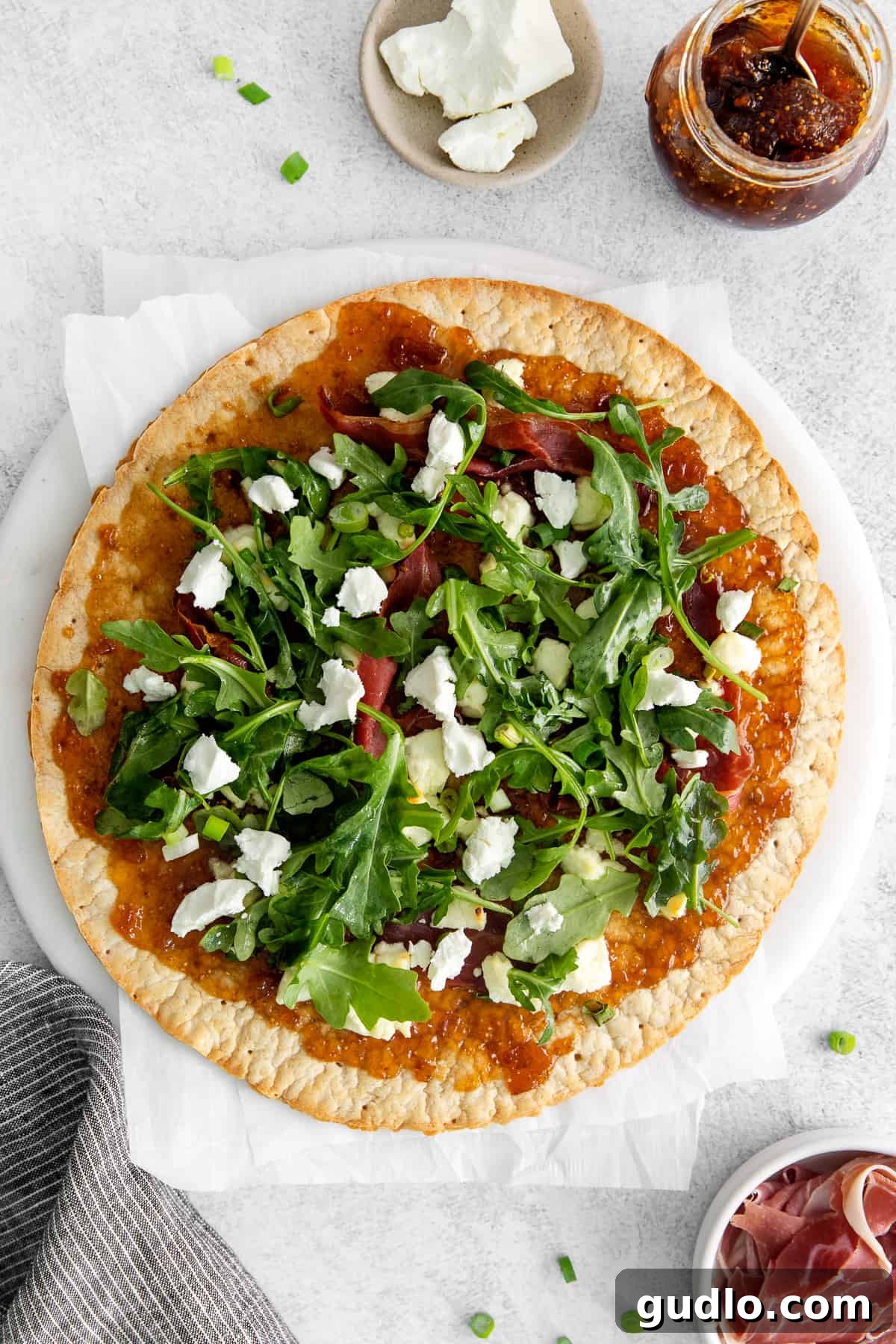 Fig and Goat Cheese Flatbread - Sweet and Savory Perfection Delicious fig and goat cheese flatbread garnished with fresh arugula on an elegant serving plate.