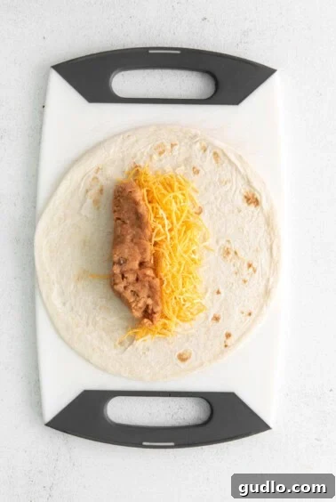 A tortilla with cheese on a cutting board, ready for filling.