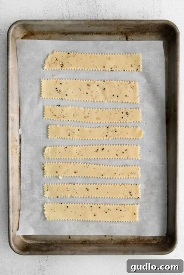Savory Homemade Cheese Crisps 6 Unbaked cheese crackers, neatly cut and arranged on a parchment-lined baking sheet, firm and ready for the freezer.