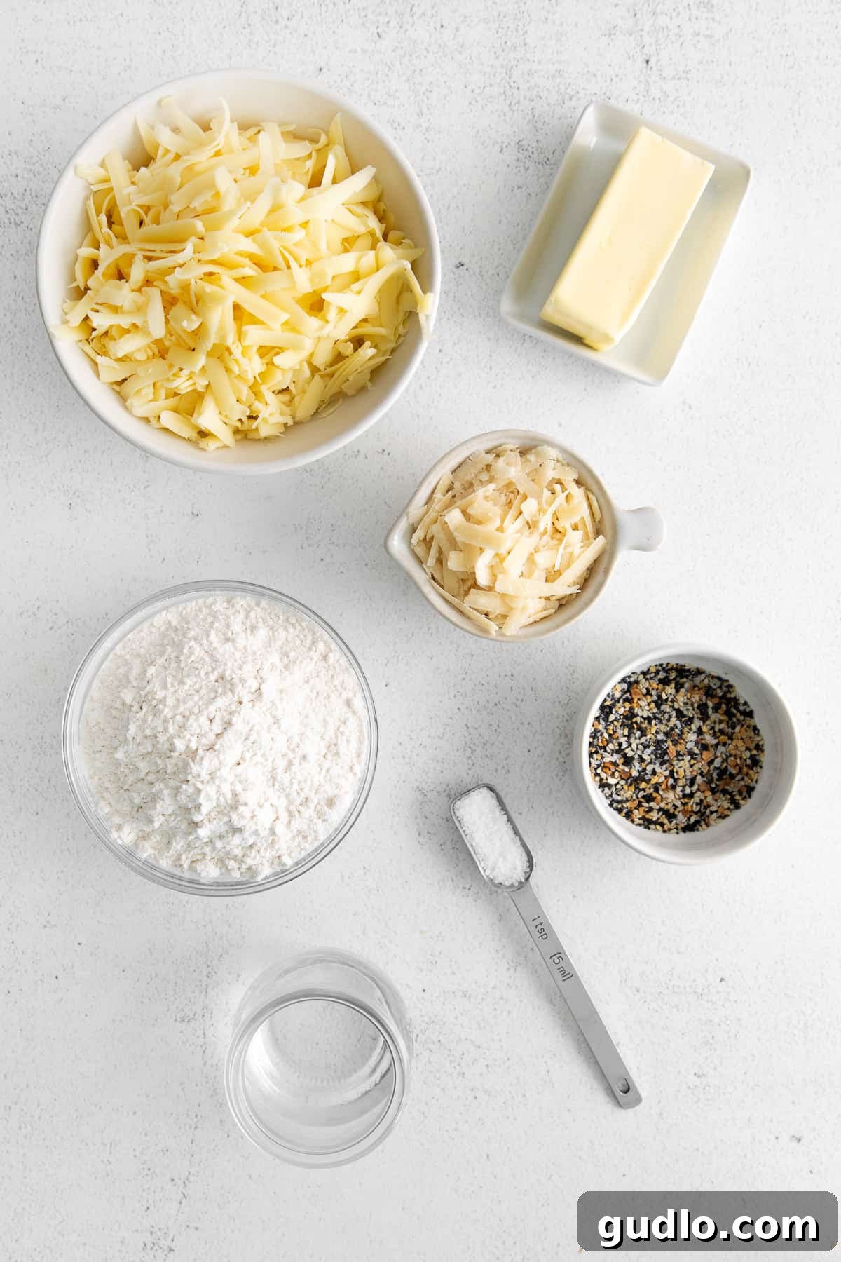 Ingredients for Cheese Crackers A collection of essential ingredients for homemade cheese crackers—cheeses, flour, butter, and seasonings—laid out neatly on a kitchen countertop, ready for preparation.