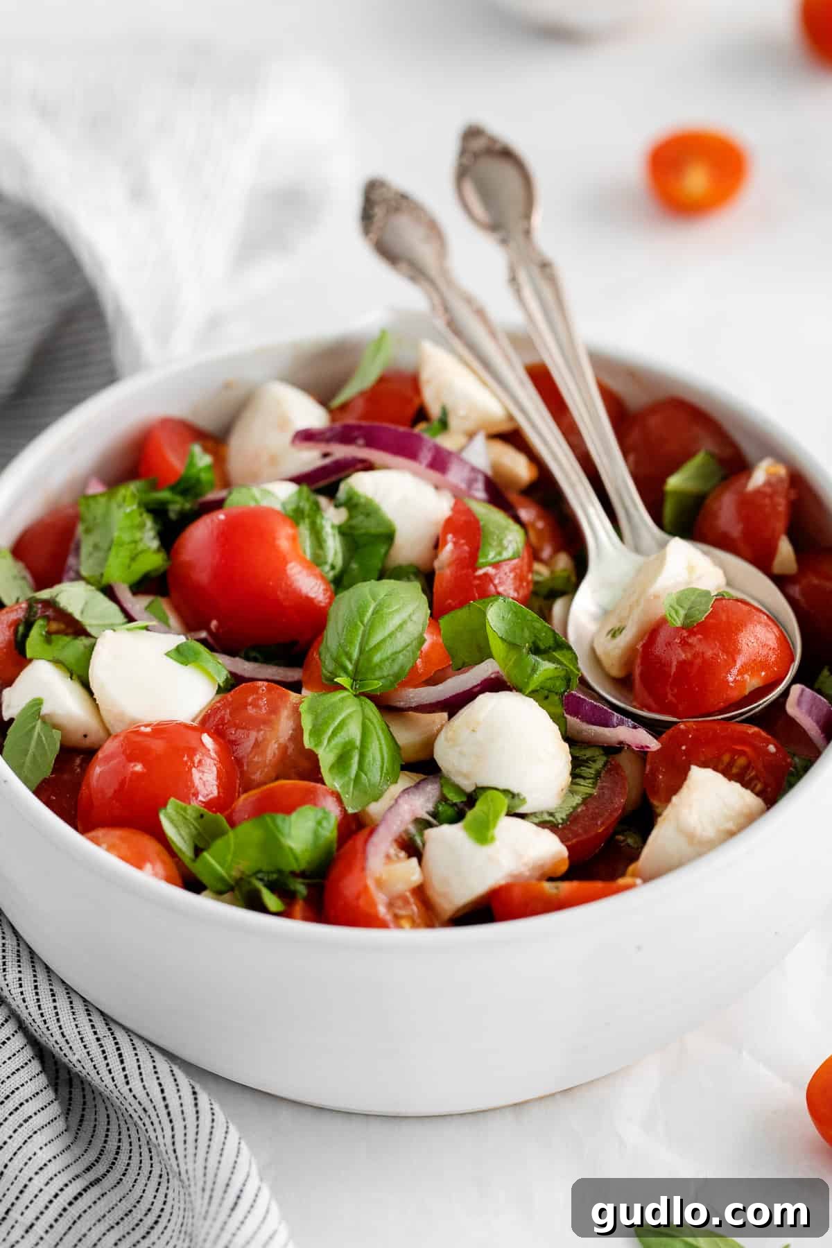 A close-up of the delicious tomato basil and mozzarella salad in a bowl, showing the fresh ingredients and rich dressing.