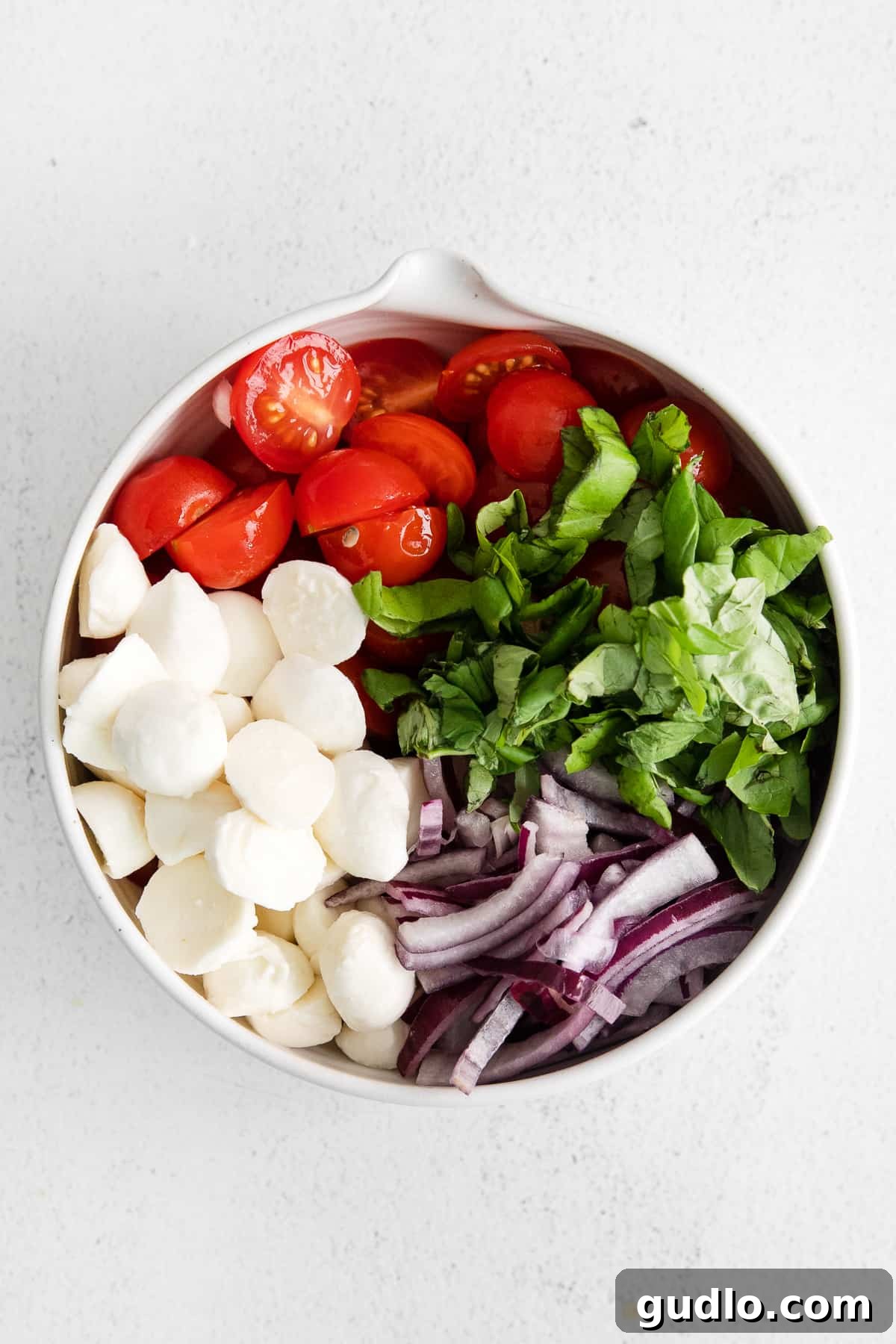 A vibrant bowl of tomato basil mozzarella salad, perfectly tossed with dressing and ready to be enjoyed.