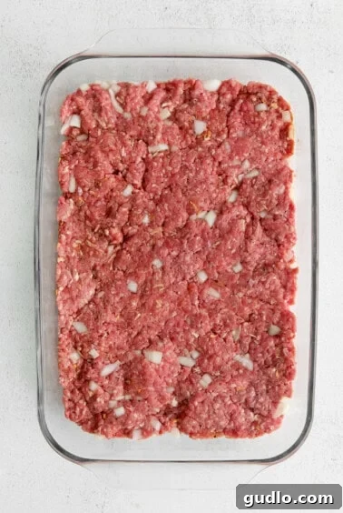 Petite Cheeseburger Perfection 4 Hamburger meat pressed flat into a casserole dish.