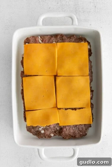 Petite Cheeseburger Perfection 5 Layers of meat and cheese on Hawaiian rolls in a baking dish.