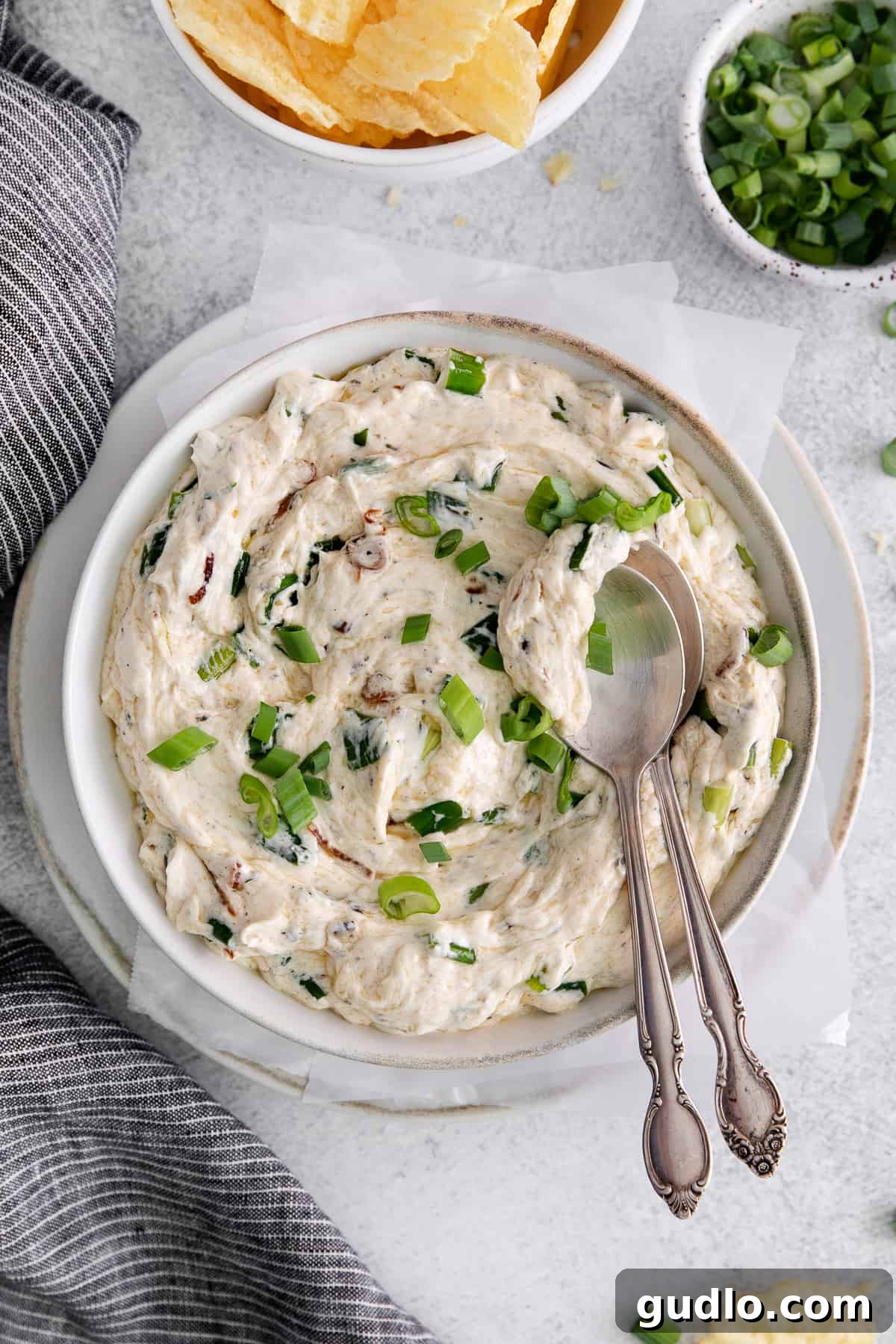 Toasted Green Onion Spread 2 A bowl of creamy Sizzling Scallion Dip, garnished with fresh green onions and served with a spoon.