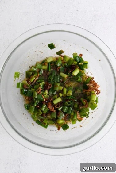 Diced green onions, paprika, and dried thyme in a heat-safe bowl.
