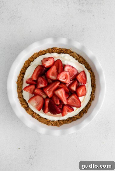 A strawberry cream cheese pie in a white dish, topped with fresh strawberries.